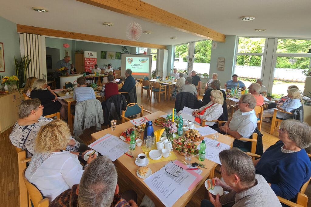 Versammlung in einem Raum mit mehreren Personen, die an Tischen sitzen