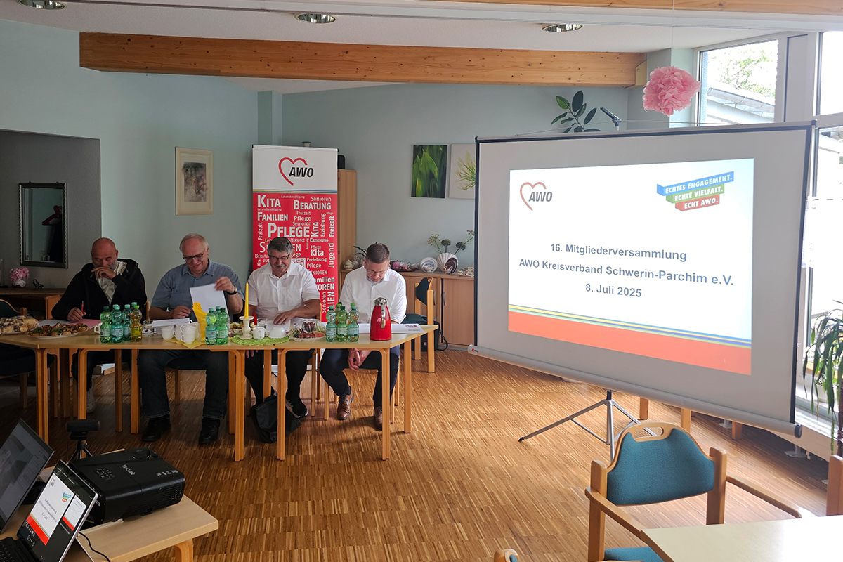 Vier Männer sitzen bei einer AWO-Versammlung an einem Tisch.