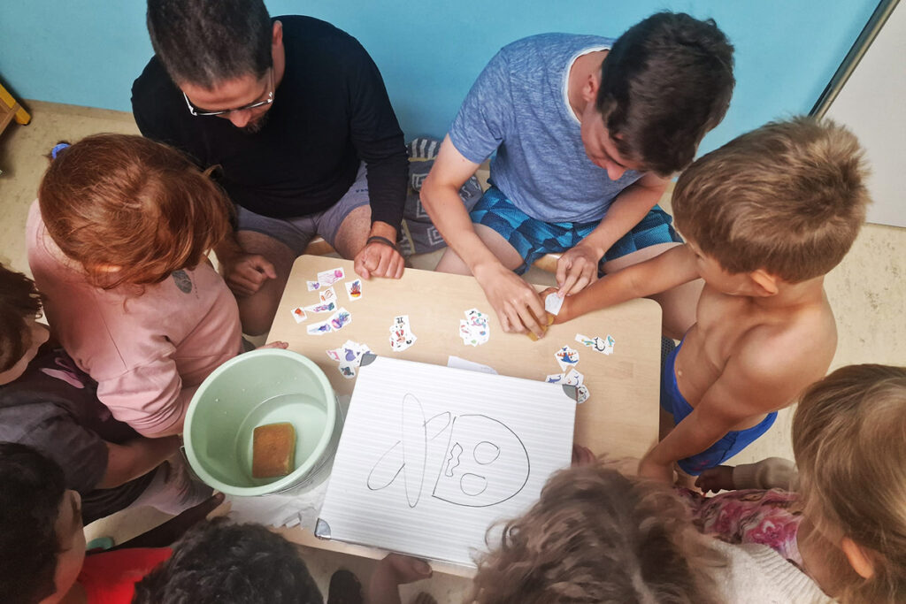 Kinder und Erwachsene arbeiten gemeinsam an einem Tisch.