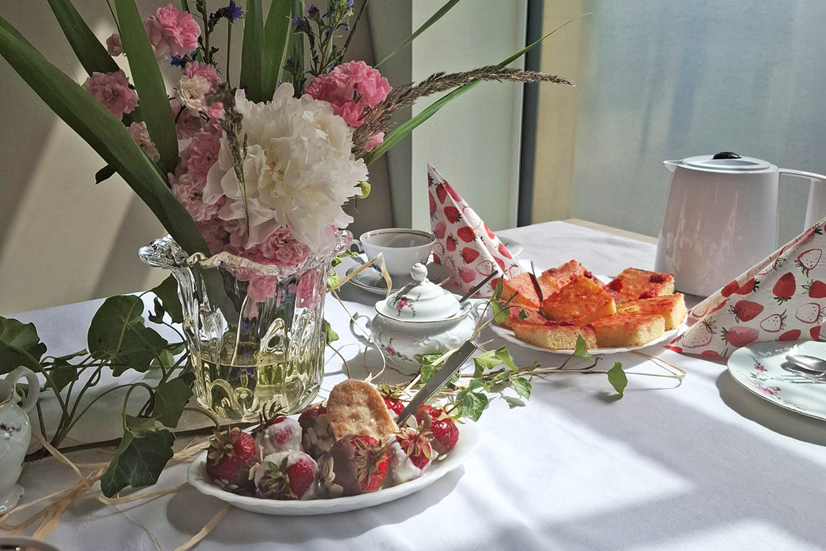 Tisch mit Blumenstrauß, Gebäck und Geschirr