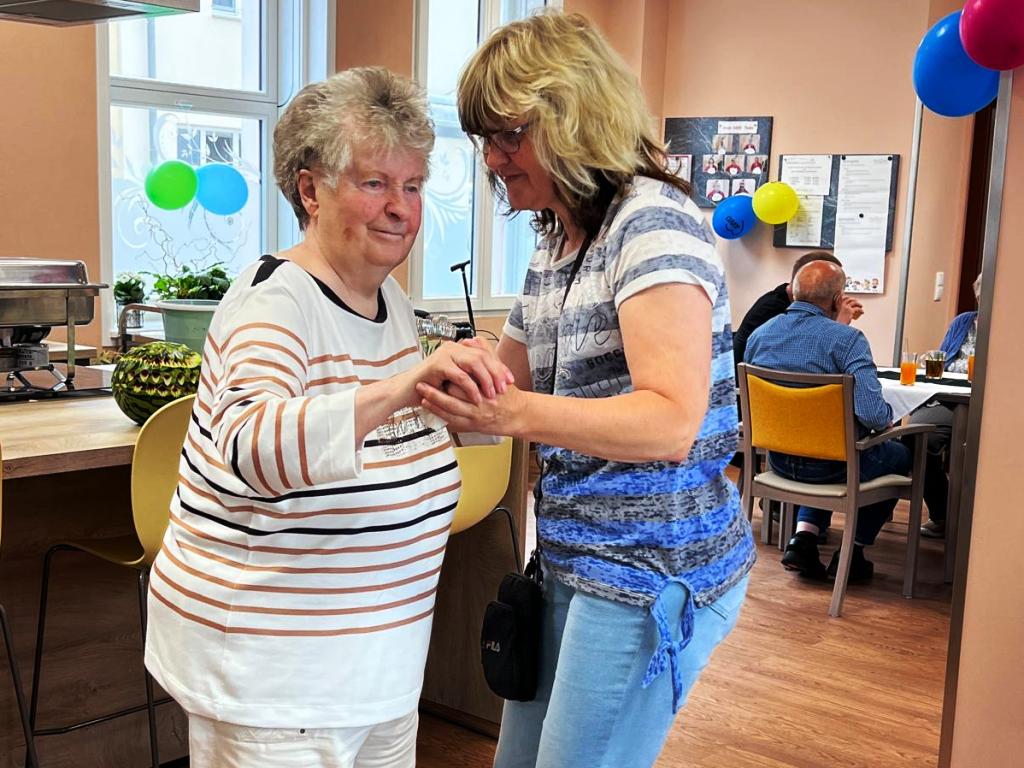 Zwei Frauen tanzen in einem Gemeinschaftsraum.