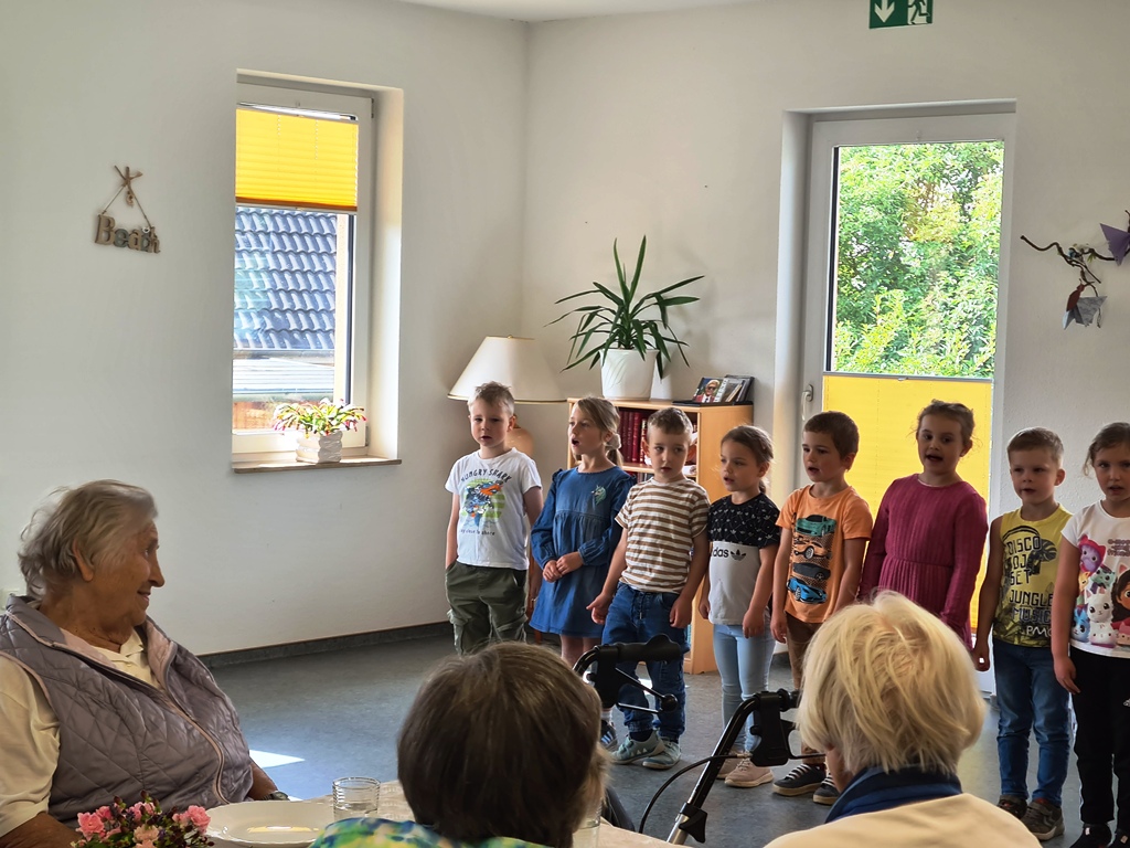 Kinder singen vor älteren Personen in einem Raum