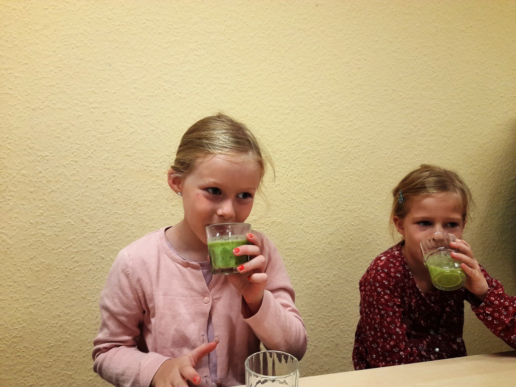 Zwei Kinder trinken grünes Getränk.