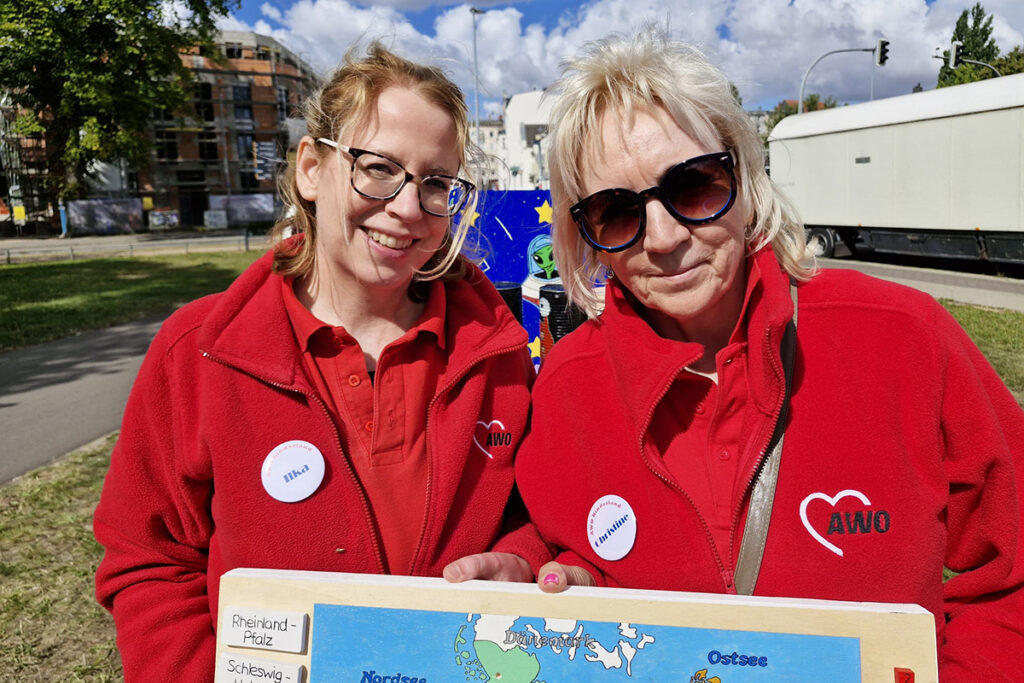 Zwei Personen in roten AWO-Jacken halten eine Karte.