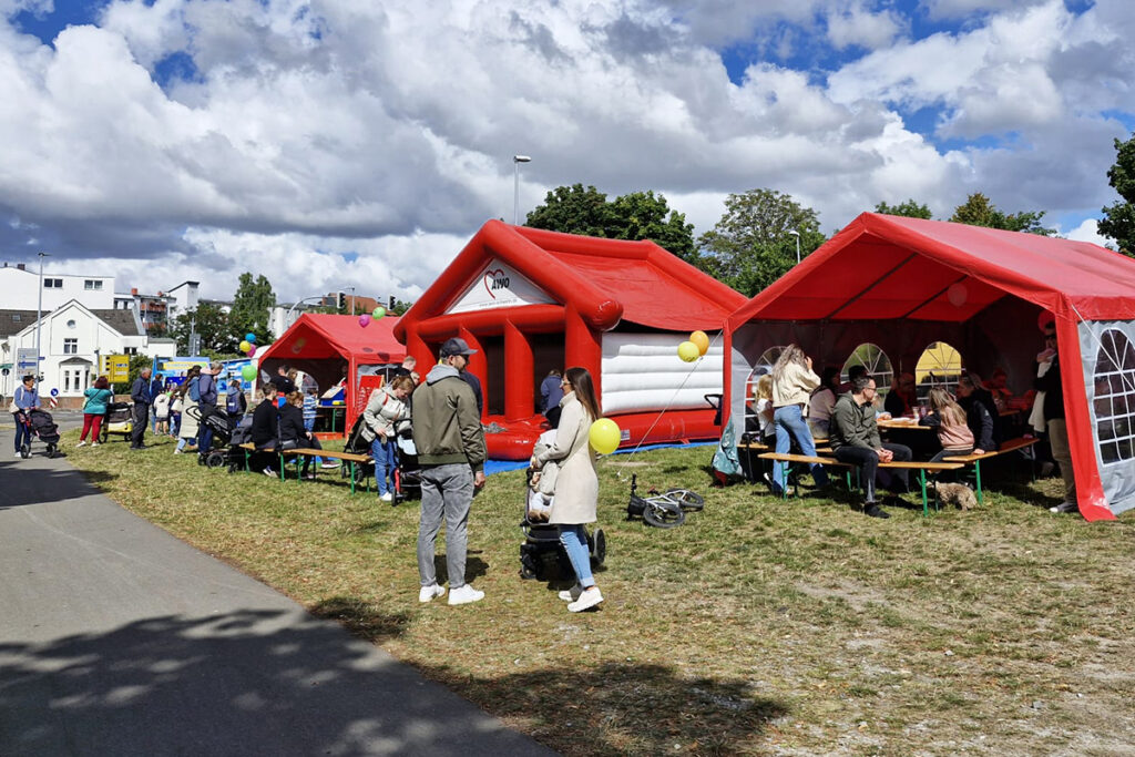 Menschen bei einem Freiluft-Event mit roten Zelten und H&uuml;pfburg