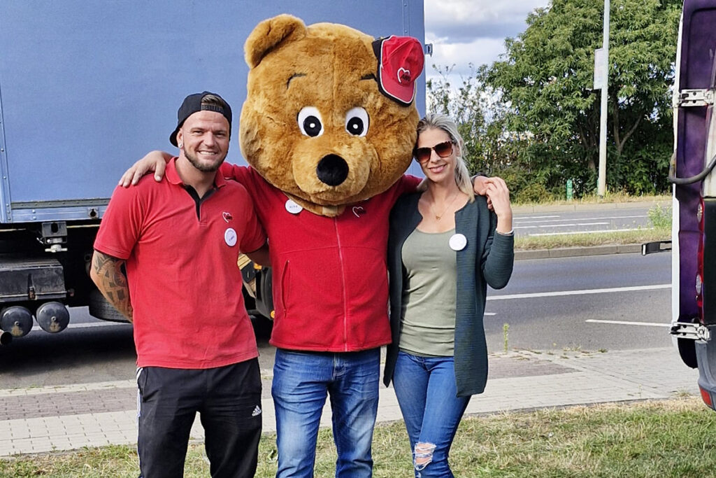 Zwei Personen mit einem Maskottchen in B&auml;renkost&uuml;m