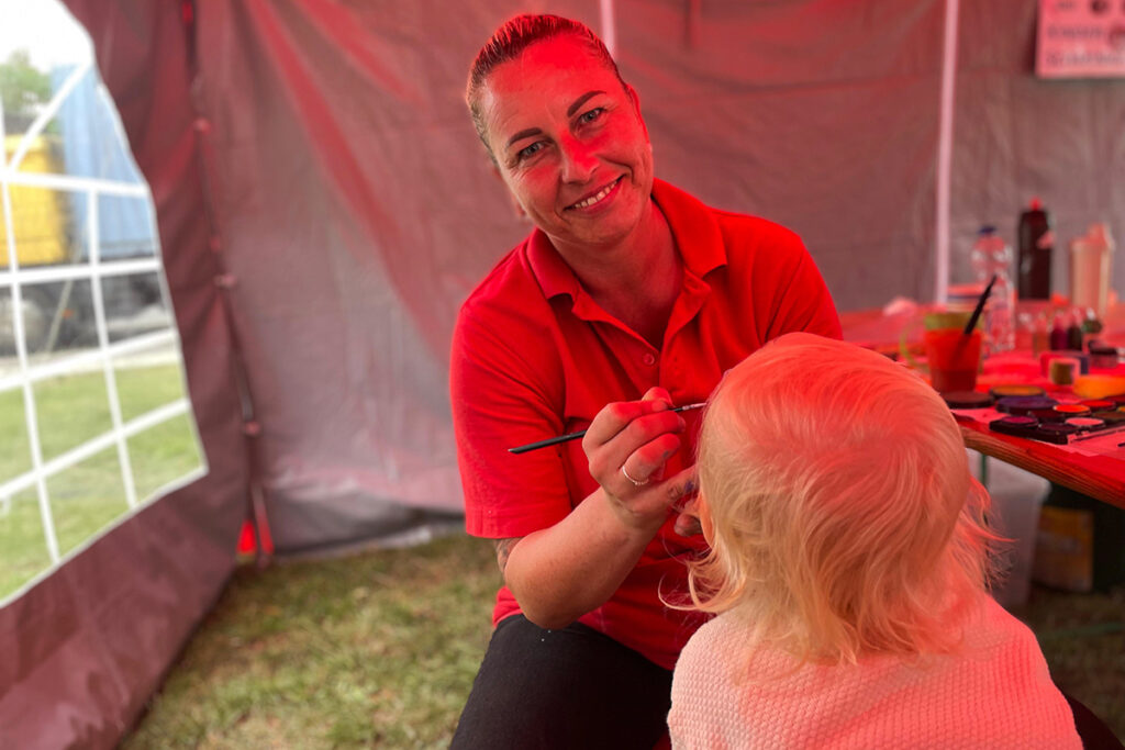 Eine Person malt das Gesicht eines Kindes in einem Zelt