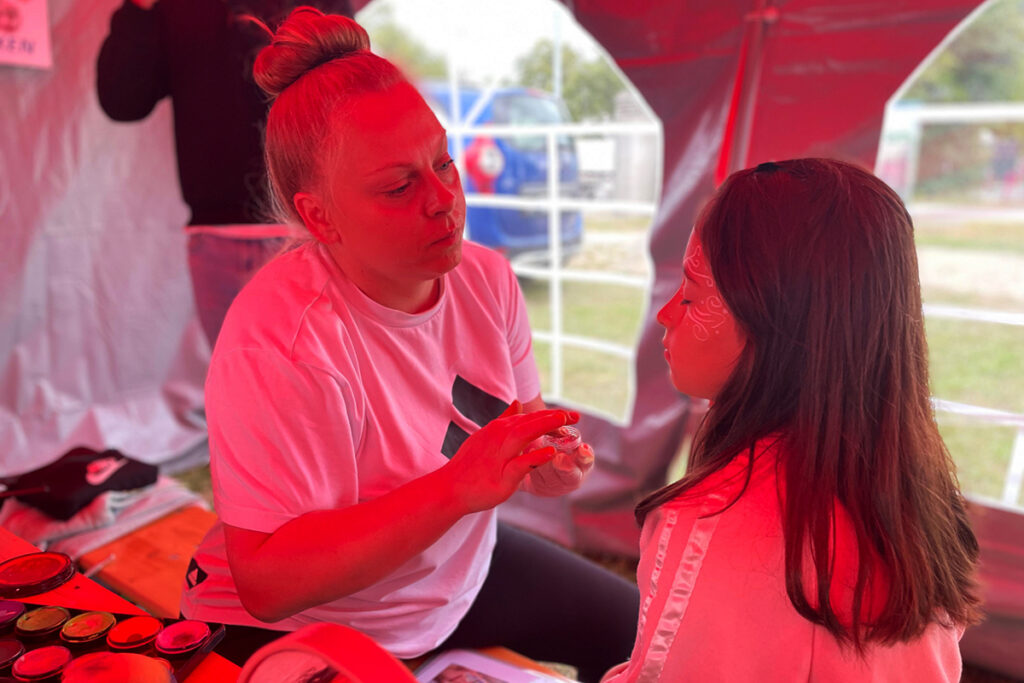 Eine Frau schminkt ein Kind in einem Zelt.