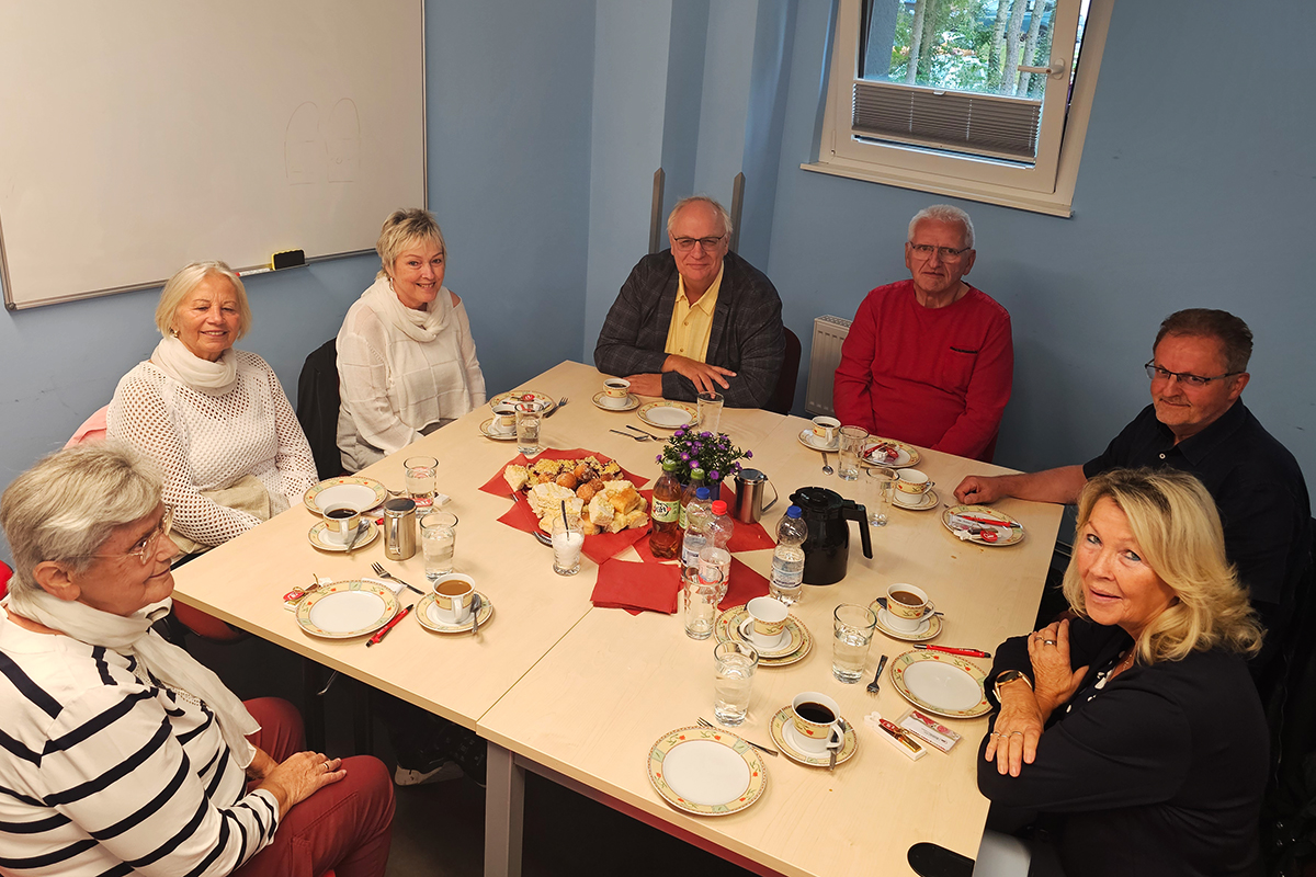 Eine Gruppe von Menschen sitzt an einem Kaffeetisch in einem Raum.