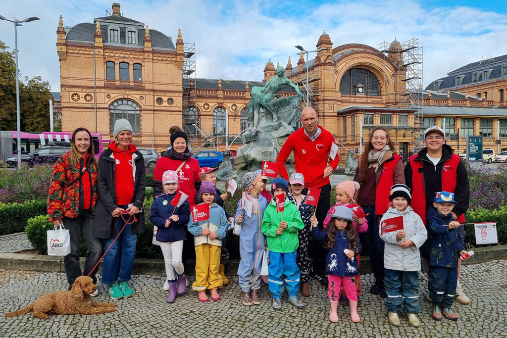 Eine Gruppe von Erwachsenen und Kindern posiert vor einem historischen Gebäude.