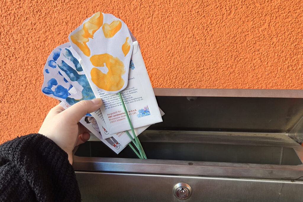 Hand holding colorful paper tulips above a mailbox