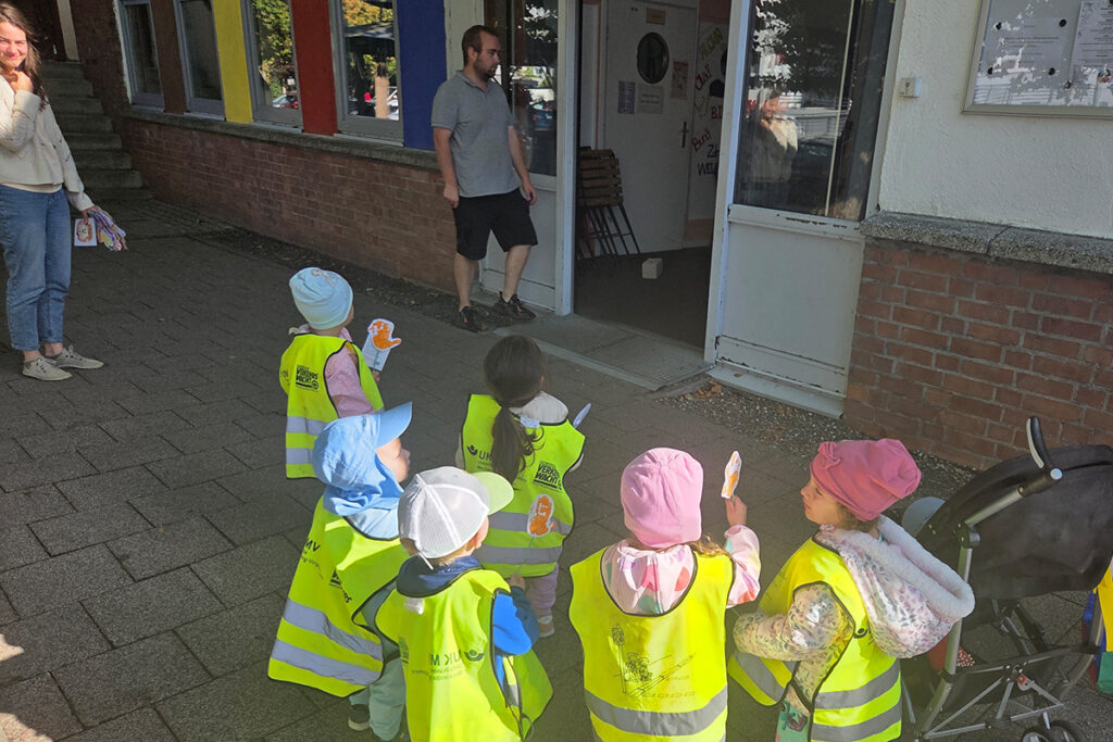 Kinder in leuchtenden Westen vor einem Geb&auml;ude