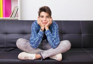 Ein Jugendlicher sitzt in entspannter Haltung auf einem Sofa