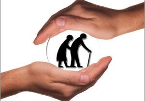 Zwei Hände umfassen eine schematische Darstellung von zwei älteren Menschen.