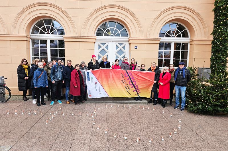 Gruppe von Menschen mit Banner und Kerzen in Herzform