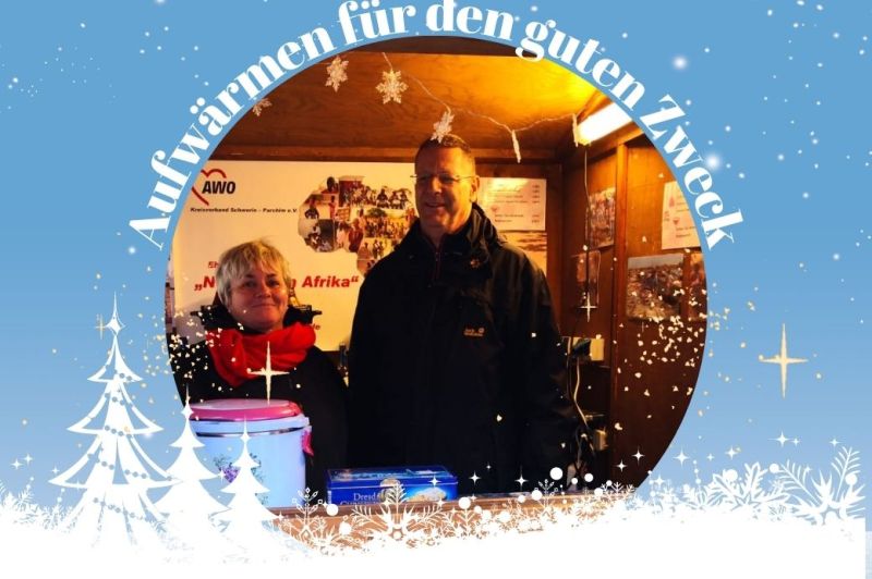 Zwei Personen stehen in einer weihnachtlich dekorierten Holzbude.