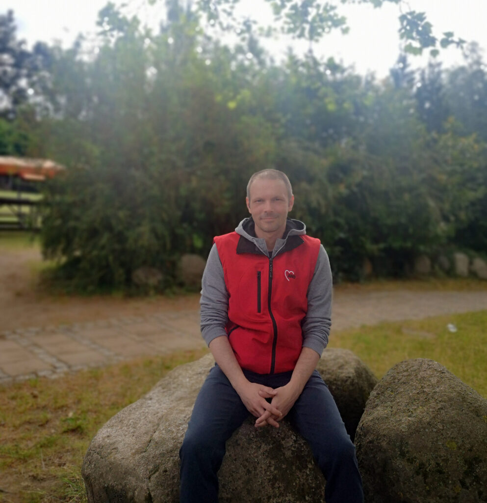 Eine Person sitzt auf einem großen Stein im Freien.