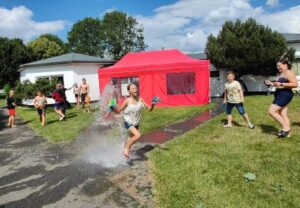 Kinder spielen an einem sonnigen Tag im Freien mit Wasserspielen.