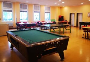 Innenansicht eines Veranstaltungsraums mit Billardtisch und Tischen.