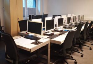 Ein Schulungsraum mit mehreren Computern auf Tischen.