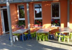 Kleiner Außenbereich mit bunten Kindermöbeln vor orangefarbener Wand.