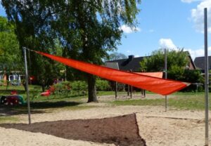 Ein orangenes Sonnensegel auf einem Spielplatz