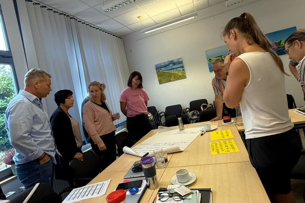 Menschen, die um einen Tisch in einem Konferenzraum stehen.