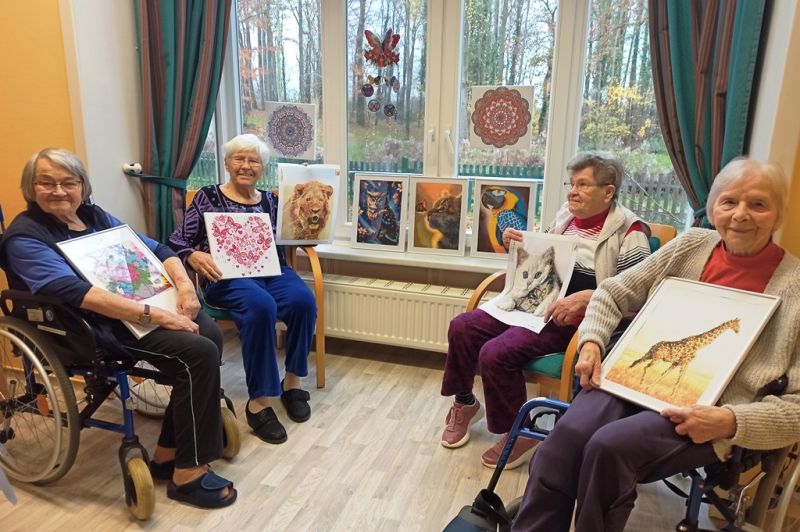 Vier ältere Frauen in einem Raum mit Gemälden auf dem Schoß