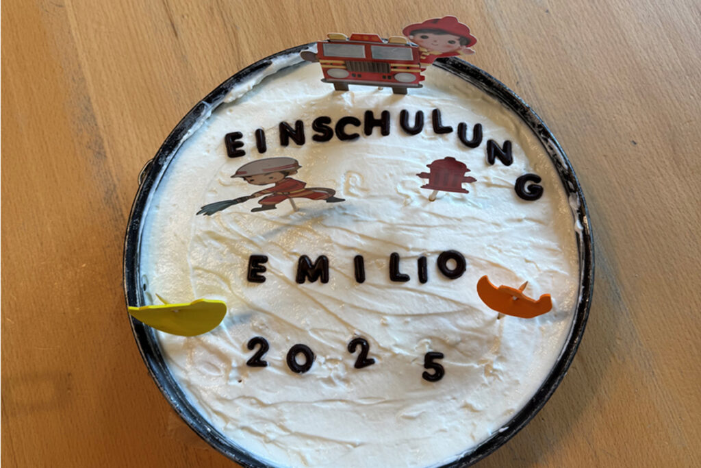 Eine runde Sahnetorte mit Dekorationen zur Einschulung.
