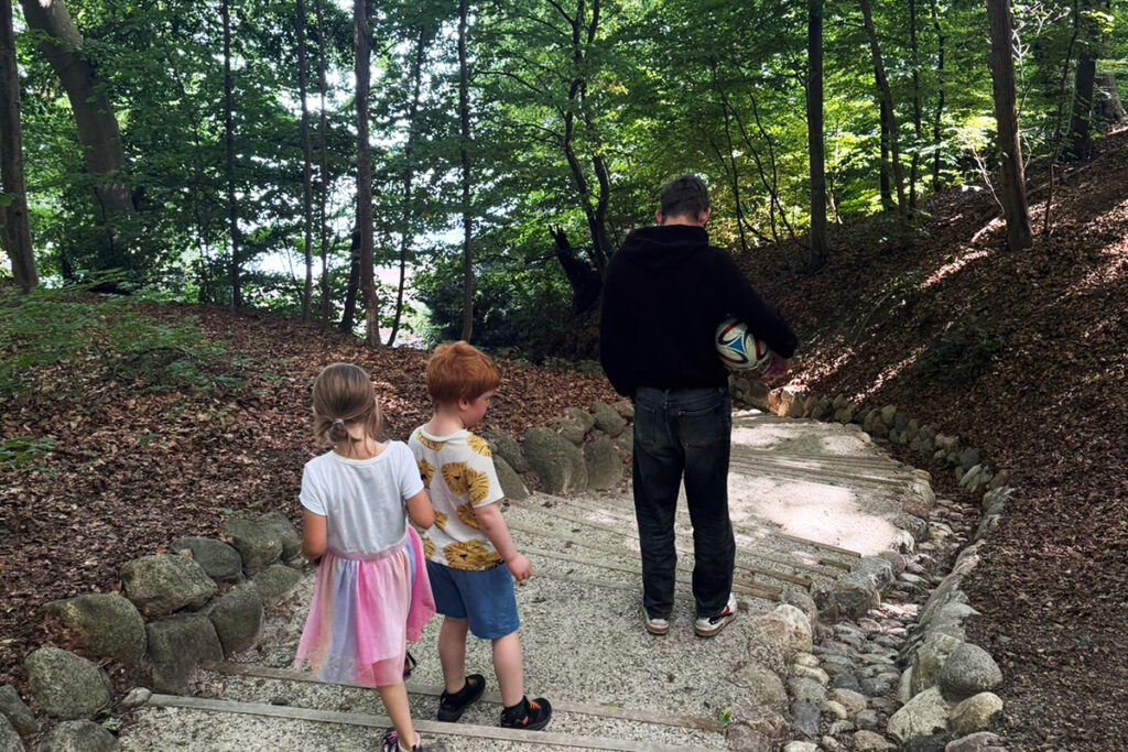 Ein Erwachsener mit zwei Kindern auf einem Waldweg.