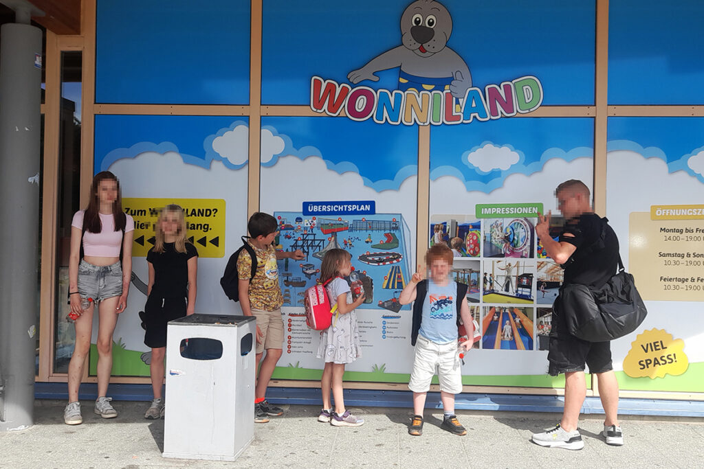 Gruppe von Menschen vor einer Wand mit 'Wonniland' Schild