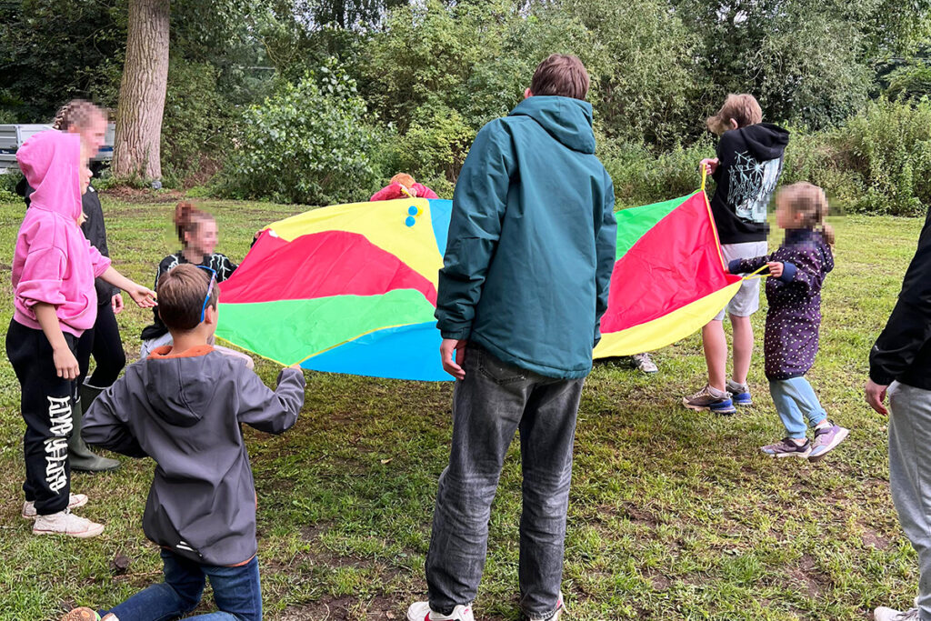 Gruppe von Kindern mit einem bunten Schwungtuch im Freien