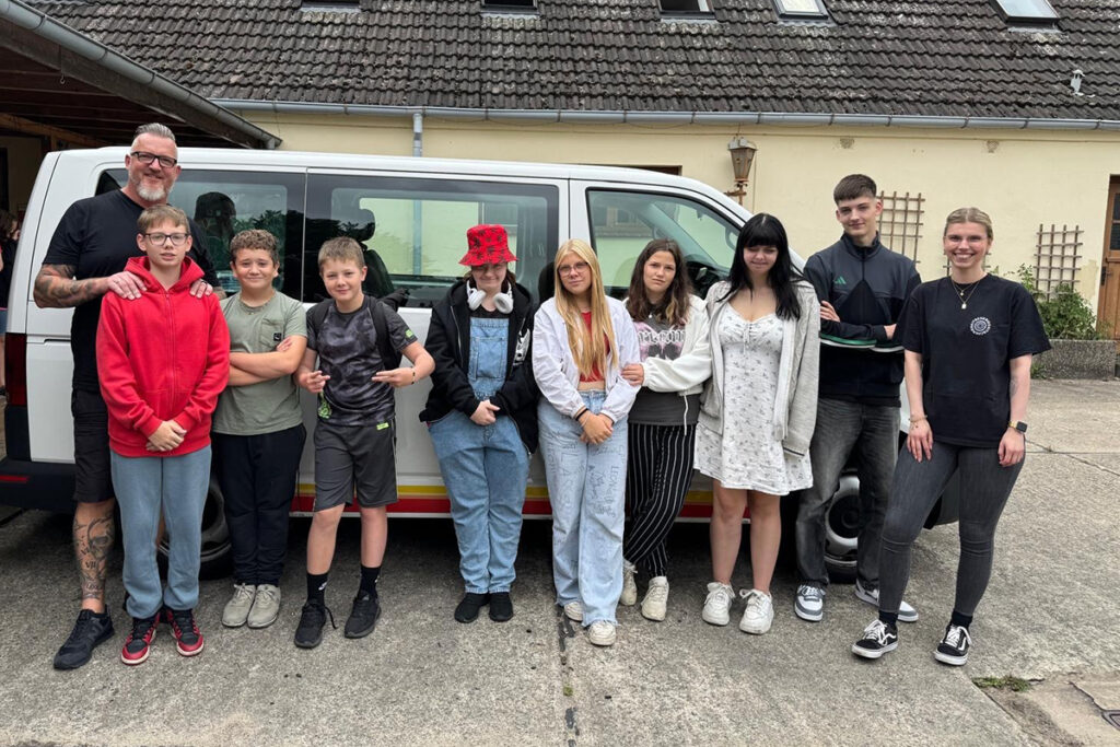 Gruppe von Menschen vor einem wei&szlig;en Fahrzeug