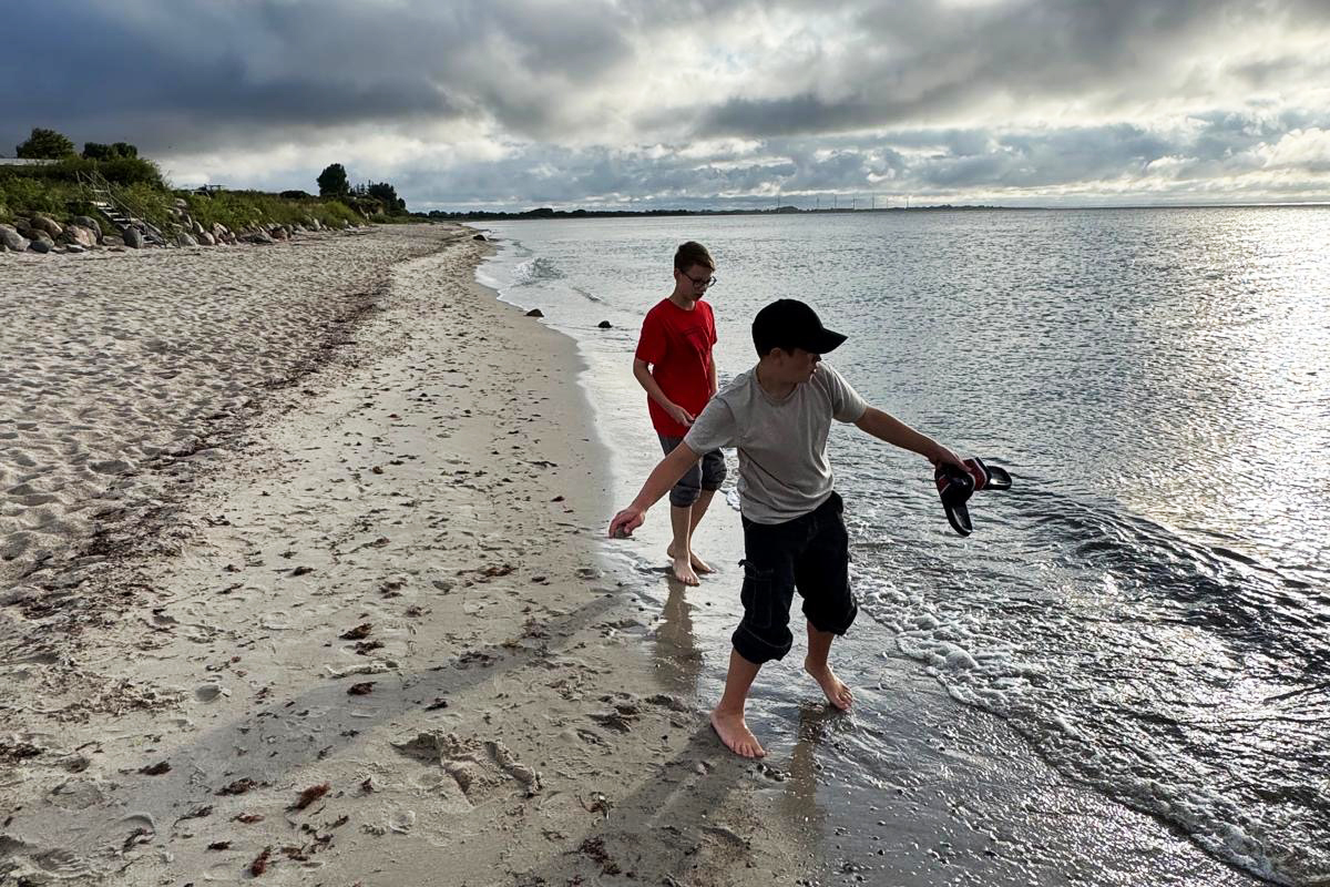 Zwei Jungen am Strand bei bewölktem Himmel.