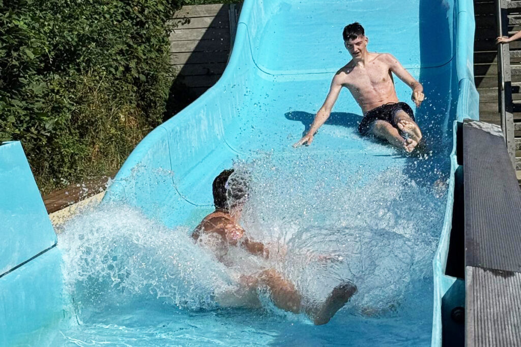 Zwei Personen rutschen eine Wasserrutsche hinunter.