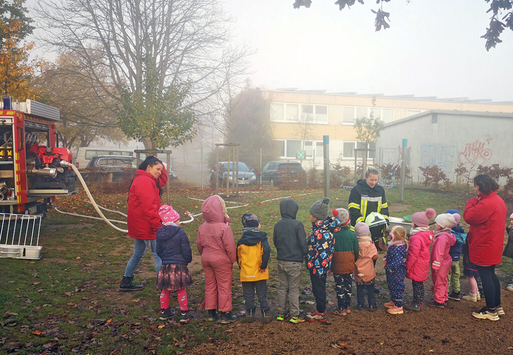 Gruppe von Kindern und Erwachsenen bei einer Feuerwehrübung