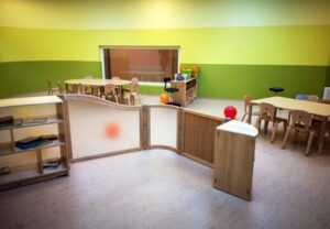 Innenraum eines Kindergartens mit Holzmöbeln und bunten Wänden.