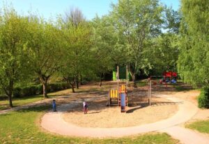 Spielplatz im Freien mit Klettergerüst und grüner Umgebung.
