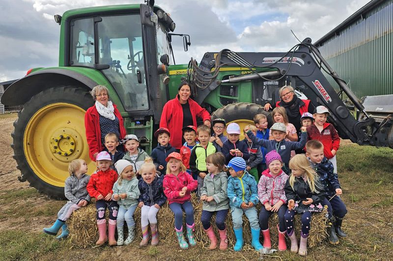 Gruppe von Kindern und Erwachsenen vor einem Traktor