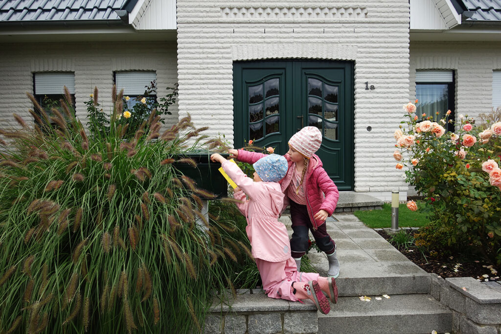 Zwei Kinder, die etwas in einen Briefkasten stecken