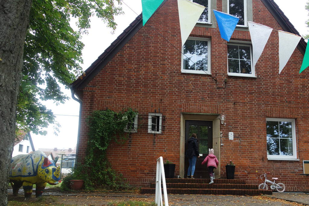 Backsteinhaus mit Wimpelgirlande und Skulptur eines Nashorns im Garten