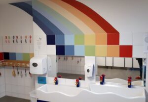 Ein Badezimmer mit zwei Waschbecken und regenbogenfarbigen Fliesen an der Wand.