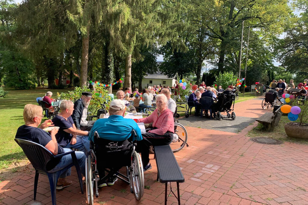 Personen sitzen im Freien bei einem Gartenfest.