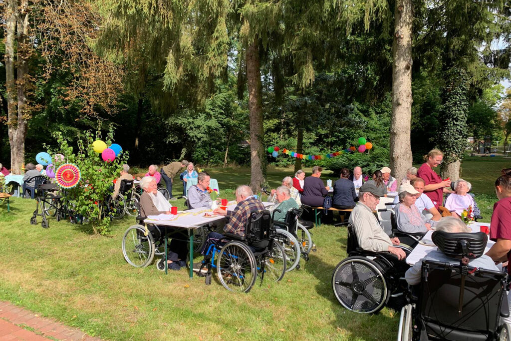 Gruppen von Menschen bei einem Gartenfest im Freien.