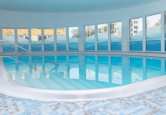 Ein moderner Innenpool mit blauen Fliesen und Glasfenstern.