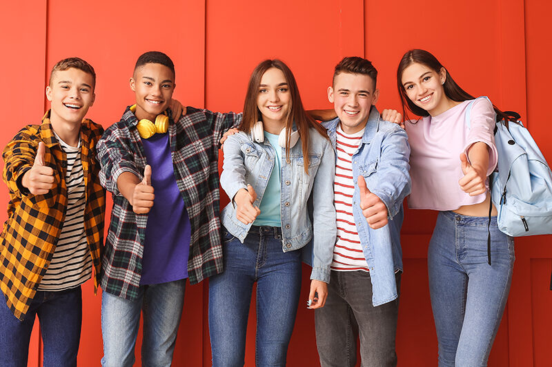 Gruppe von fünf Jugendlichen, die Daumen hoch zeigen.