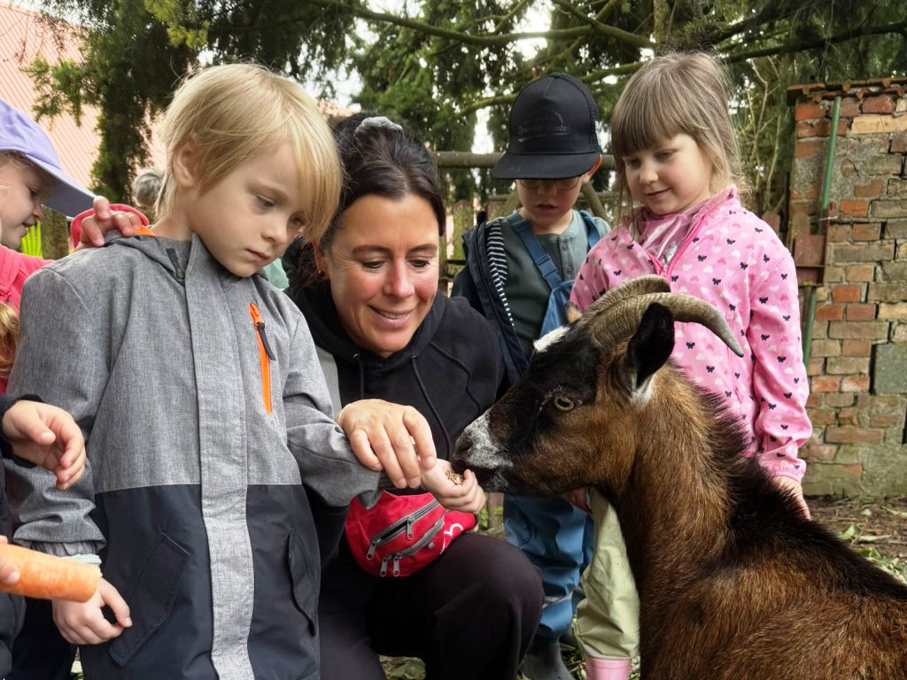 Kinder und Erzieherin mit einer Ziege