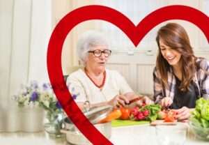 Ältere Frau und jüngere Frau beim Gemüseschneiden am Tisch