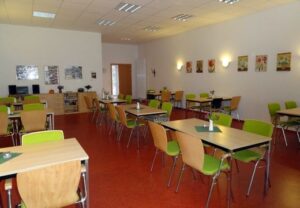 Ein heller Gemeinschaftsraum mit Tischen und Stühlen