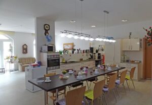 Ein heller Gemeinschaftsraum mit großer Küche und Esstisch.